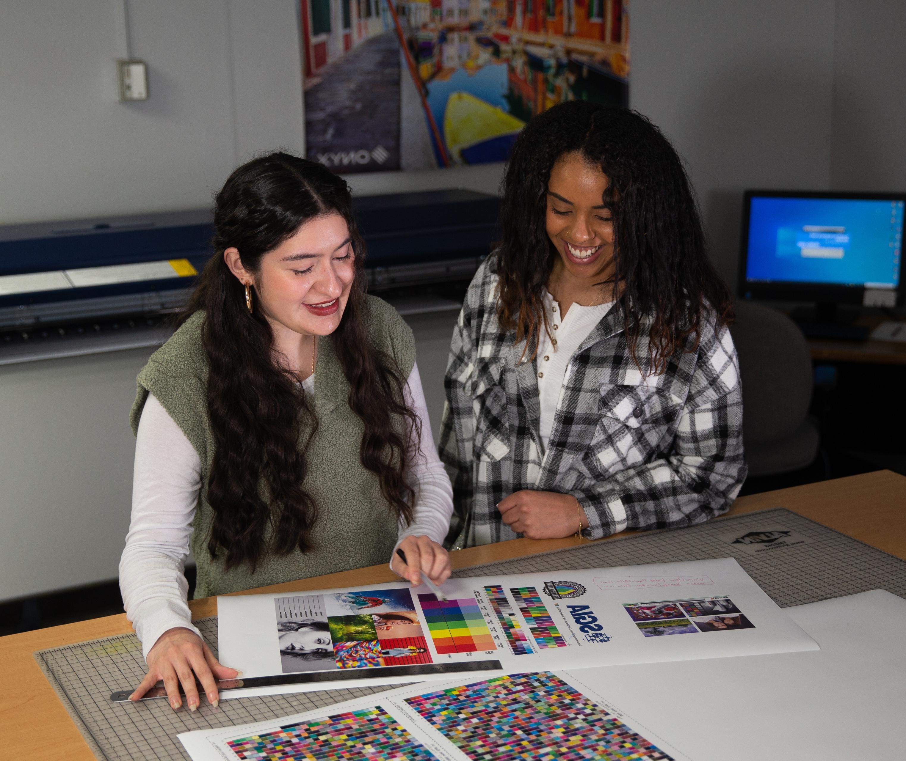 两名就读于BGSU视觉传达技术专业的女生正在看她们正在做的一个项目的彩色图表