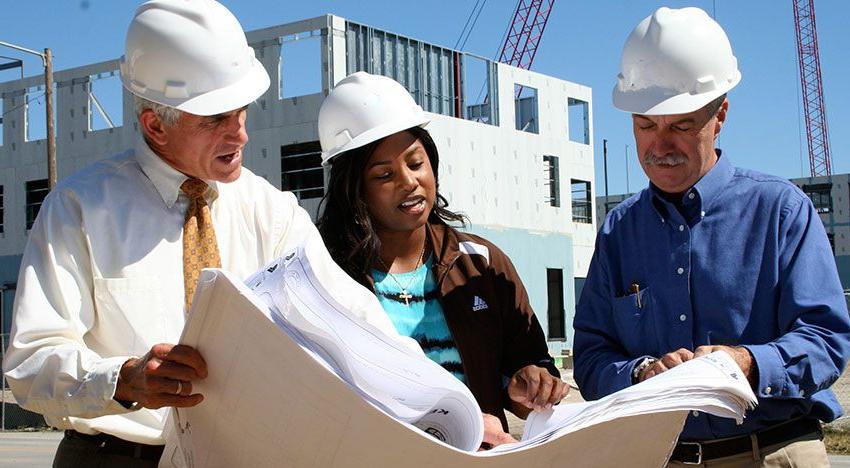 Photo of two graduate professors working with a graduate student on a job site