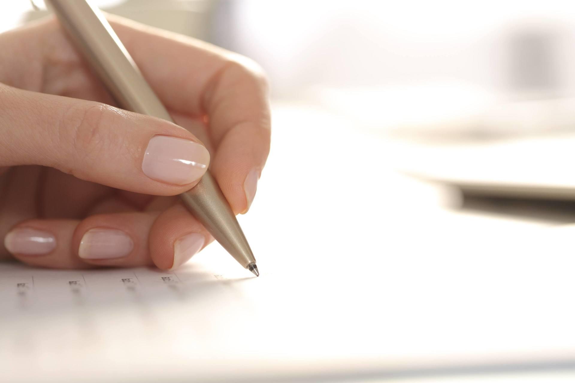 Woman hand filling out form with pen on a desk